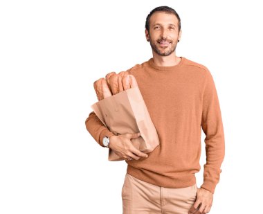 Elinde ekmek dolu kese kağıdıyla genç ve yakışıklı bir adam. Pozitif ve mutlu görünüyor. Kendine güvenen bir gülümsemeyle, dişlerini gösteriyor. 