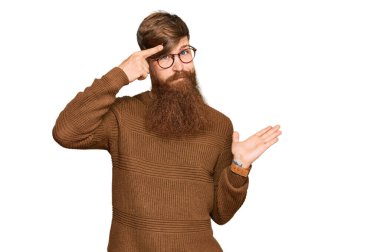 Genç İrlandalı kızıl elbiseli, gözlüklü, kafası karışmış ve avuç içi açık bir şekilde fotokopi alanını gösteren ve alnını işaret eden bir adam. Bunu bir düşün.. 