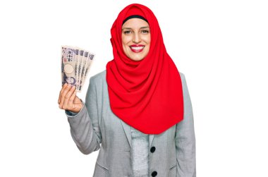 Güzel İspanyol kadın elinde Japon Yen banknotları tutan tesettüre bürünmüş. Pozitif ve mutlu görünüyor. Kendine güvenen bir gülümsemeyle dişlerini gösteriyor. 