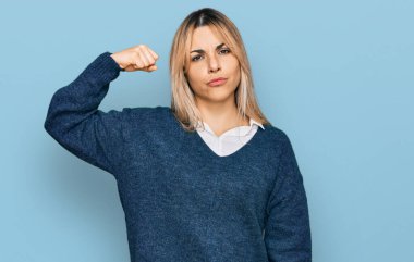 Gündelik kıyafetler giyen genç beyaz kadın güçlü kol kası gösteren, kendinden emin ve gururlu biri. 