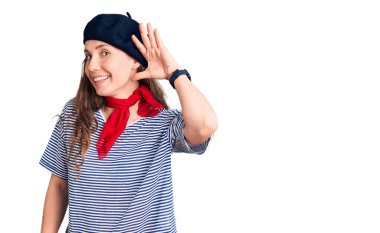 Fransız beresi ve çizgili tişört giyen genç, sarışın bir kadın. Kulaktan kulağa gülümseyen ve dedikodulara kulak misafiri olan. Sağırlık kavramı. 