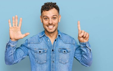 Günlük kot ceket giyen genç İspanyol adam altı numaralı parmaklarıyla gülümseyerek kendinden emin ve mutlu görünüyor.. 