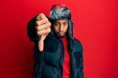 Sakallı, kışlık şapkalı, ceketli, mutsuz, reddedilmiş ve olumsuz jestli genç Afrikalı Amerikalı bir adam. kötü ifade. 