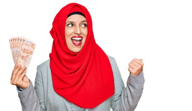 İslami tesettür takan güzel İspanyol kadın elinde Türk lirası banknotlar başparmağıyla yan tarafa bakıp mutlu bir şekilde gülümsüyor. 