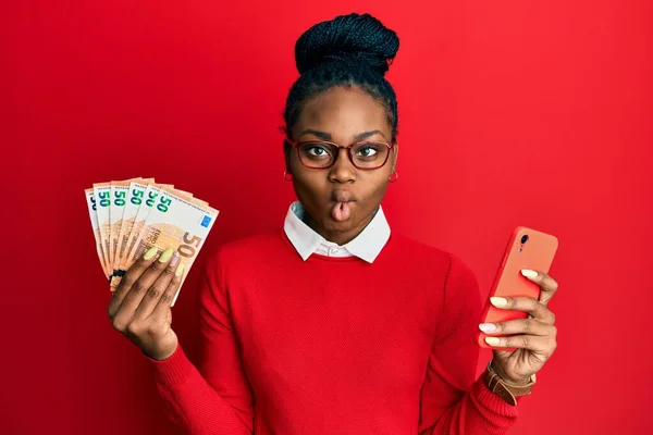 Joven Mujer Afroamericana Usando Smartphone Con Billetes Euros Haciendo Cara —  Fotos de Stock