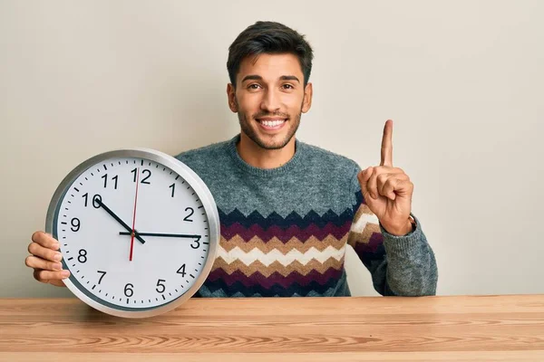 Joven Hombre Guapo Sosteniendo Gran Reloj Sonriendo Con Una Idea — Foto de Stock