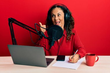 Güzel orta yaşlı bir kadın radyo stüdyosunda çalışıyor. Parmağını yana doğru uzatıyordu. Ağzını açıp gülümsüyordu. 