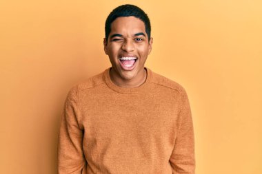 Genç, yakışıklı, süveter giyen, seksi bir ifadeyle kameraya bakan, neşeli ve mutlu yüzlü bir İspanyol.. 