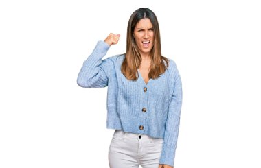 Kızgın ve kızgın giyinmiş genç bir kadın öfkeyle bağırırken sinirli ve öfkeli bir şekilde yumruk kaldırıyor. öfke ve agresif konsept. 