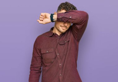 Latin kökenli genç adam sıradan kıyafetler giyip gözlerini kollarıyla kapatıyor, ciddi ve üzgün görünüyor. Görme, saklama ve reddetme konsepti 