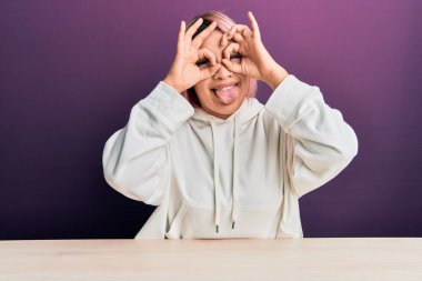 Masada oturan pembe saçlı İspanyol kadın. Dürbün gibi güzel hareketler yapıyor. Gözleri parmaklarından bakıyor. çılgın ifade. 