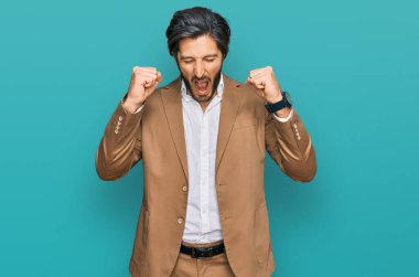 Genç İspanyol bir adam iş kıyafetleri giyiyor kızgın ve kızgın yumruklarını kaldırıyor öfkeyle bağırırken sinirli ve öfkeli. öfke ve agresif konsept. 