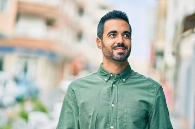 Genç İspanyol adam gülümseyerek şehirde mutlu mesut dikiliyor..