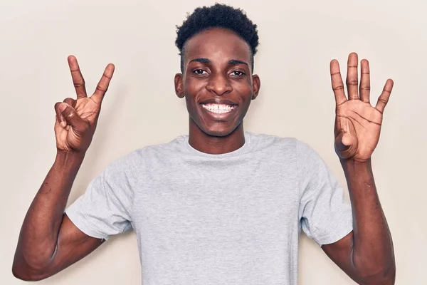 自信を持って幸せな笑顔ながら 若いアフリカ系アメリカ人の男性は カジュアルな服を着て指の数7で示すと指摘します — ストック写真