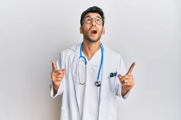 Jovem Homem Bonito Vestindo Uniforme Médico Estetoscópio Espantado Surpreso Olhando — Fotografia de Stock