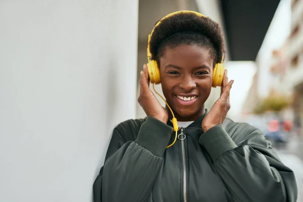 Young african american girl smiling happy using headphones at the city.