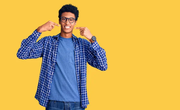 年轻的非洲裔美国人 身穿休闲装 戴着眼镜 笑容满面 用手指 牙齿和嘴指指指点点 牙齿健康概念 — 图库照片