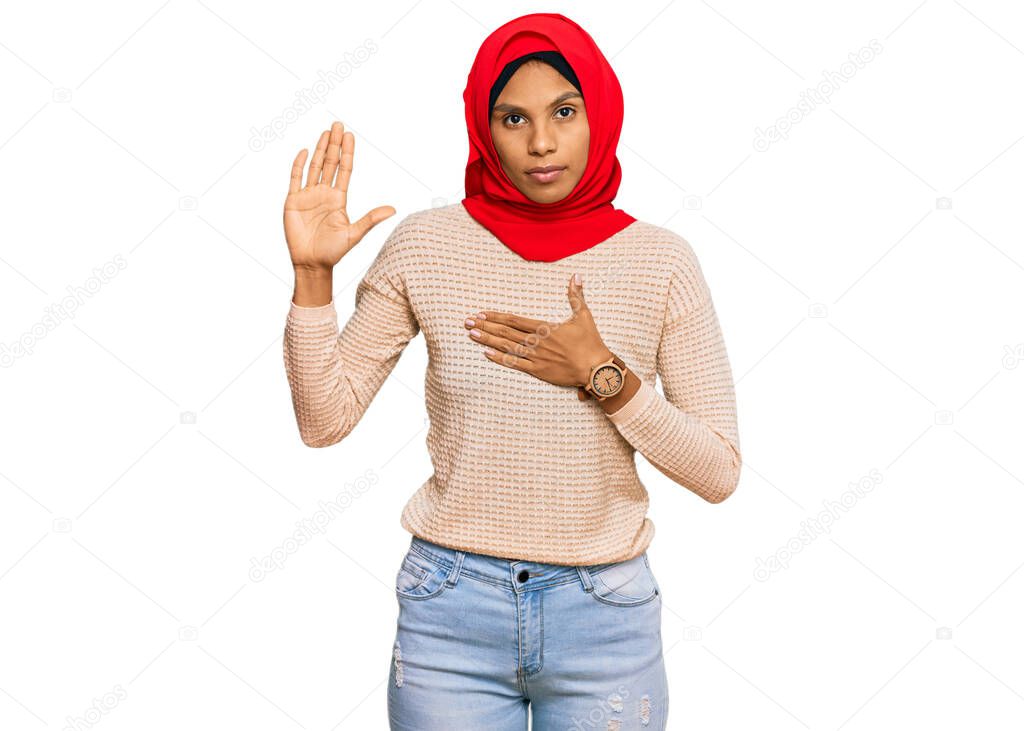 Young african american woman wearing traditional islamic hijab scarf swearing with hand on chest and open palm, making a loyalty promise oath 