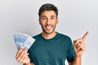 1000 Güney Koreli 'yi elinde tutan yakışıklı genç adam para kazandı. Gülümseyerek mutlu bir şekilde el ve parmak kenarı gösterdi. 