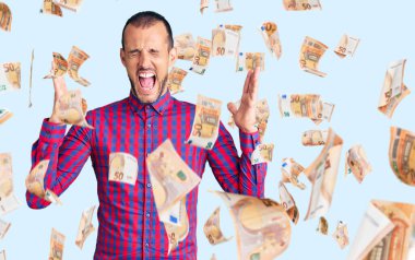 Gündelik kıyafetler giyen genç, çılgın ve çılgın başarıyı kutlayan kollarını kaldırmış, gözlerini kapatmış heyecanlı çığlıklar atan yakışıklı bir adam. Kazanan konsept