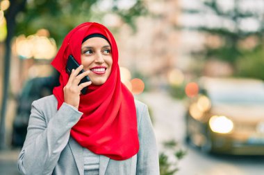 Şehirdeki akıllı telefondan konuşan tesettürlü genç Arap iş kadını..