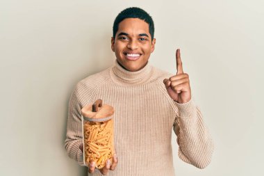 Genç, yakışıklı İspanyol adam elinde makarna kavanozuyla gülümseyen bir fikir ya da soru işareti ile gülümseyen mutlu bir yüz, bir numara. 