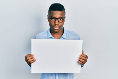 Gözlük takan, boş pankart tutan Afro-Amerikan genç adam yüzünde ciddi bir ifadeyle gevşedi. Basit ve doğal bir şekilde kameraya bakıyorsun.. 