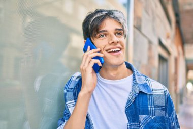 Genç İspanyol adam gülümsüyor. Şehirdeki akıllı telefondan konuşuyor..