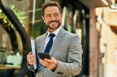 Şehirdeki akıllı telefondan gülümseyen orta yaşlı bir işadamı..