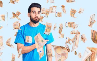 Sakallı, sıradan tişörtlü genç ve yakışıklı bir adam endişeli, endişeli ve şaşırmış bir ifade takınıyor.