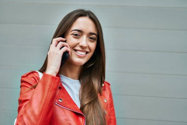 Genç İspanyol kadın gülümsüyor. Şehirdeki akıllı telefondan konuşuyor..