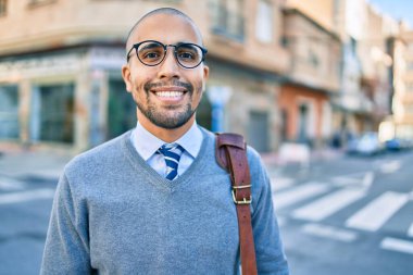 Genç Afrikalı Amerikalı iş adamı gülümseyerek şehirde mutlu bir şekilde yürüyor..
