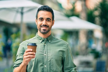 Genç İspanyol gülümseyen mutlu bir adam şehirde kahve içiyor..