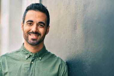 Genç İspanyol adam gülümseyerek şehirde mutlu mesut dikiliyor..