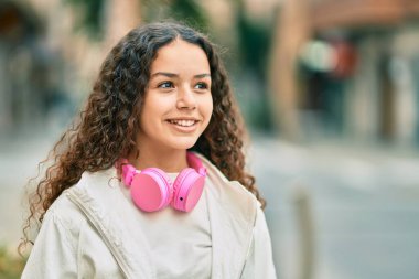 Şehirde kulaklık takıp gülümseyen İspanyol çocuk..