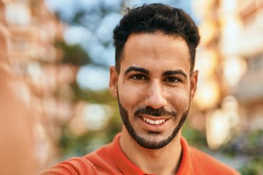 Genç İspanyol gülümseyen adam şehirde fotoğraf çekerken mutlu oluyor..