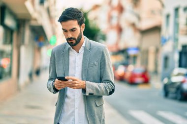 Şehirde akıllı telefon kullanan Latin asıllı genç bir işadamı..