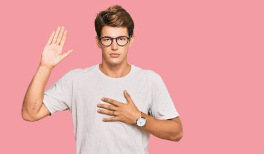 Yakışıklı beyaz bir adam günlük kıyafetler ve gözlük takıyor. Göğsü ve avucu açık küfür ediyor. Sadakat yemini ediyor. 