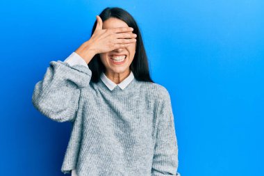 Gündelik kıyafetler giyen, gülümseyen ve gülümseyen genç İspanyol kadın şaşırmak için gözlerini kapatıyor. kör kavram. 