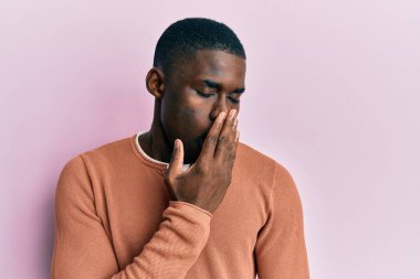 Gündelik giysiler giyen genç Afro-Amerikalı adam ağzını eliyle kapatmaktan sıkıldı. Huzursuz ve uykulu.. 