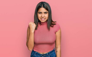 Gündelik tişört giyen genç İspanyol kız öfkeyle bağırırken kızgın ve kızgın bir şekilde yumruğunu kaldırıyor. öfke ve agresif konsept. 