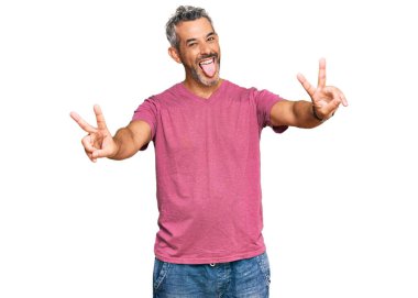 Orta yaşlı, gri saçlı, günlük kıyafetler giyen, dili dışarı fırlayan, zafer işareti yapan bir adam. İki numara.. 