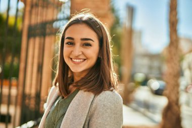 Genç İspanyol kız gülümseyerek şehirde mutlu mesut dikiliyor..