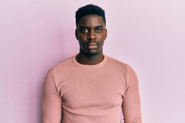 Yüzünde ciddi bir ifade olan sıradan kıyafetler giyen yakışıklı bir zenci. Basit ve doğal bir şekilde kameraya bakıyorsun.. 