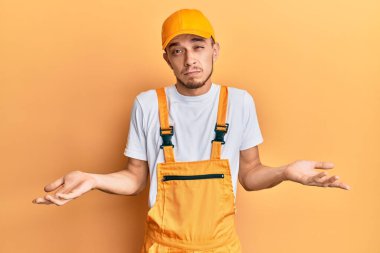 Tamirci üniforması giyen İspanyol genç adam hiçbir şeyden habersiz ve kolları açık, hiçbir fikri yok.. 