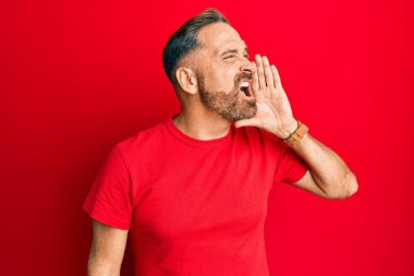 Yakışıklı, orta yaşlı, sıradan kırmızı tişörtlü, el ele tutuşup bağıran bir adam. iletişim konsepti. 