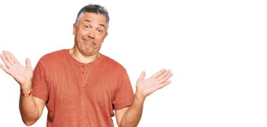 Handsome middle age man wearing casual clothes clueless and confused expression with arms and hands raised. doubt concept.  clipart