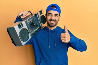 Genç İspanyol adam elinde teyp, müzik dinliyor mutlu ve olumlu gülümsüyor, başparmağıyla mükemmel ve onay işareti yapıyor. 