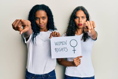 Afrika kökenli Amerikalı anne ve kız ellerinde kadın hakları pankartı kamerayı işaret ediyor ve sen kendine güvenen bir jestsin. 