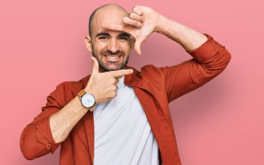 Gündelik kıyafetler giyen, gülümseyen, elleri ve parmakları gülen yüzlü, çerçeveli bir İspanyol. yaratıcılık ve fotoğrafçılık kavramı. 